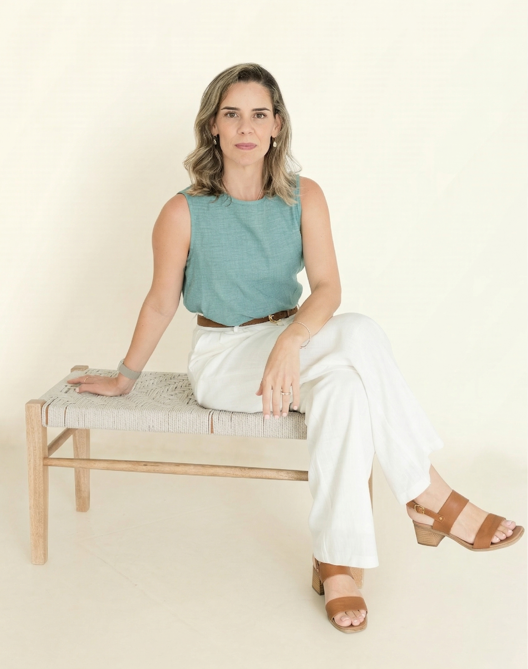 Retrato de uma mulher sentada em cadeira, em ambiente neutro, representando Flavia Nogueira.